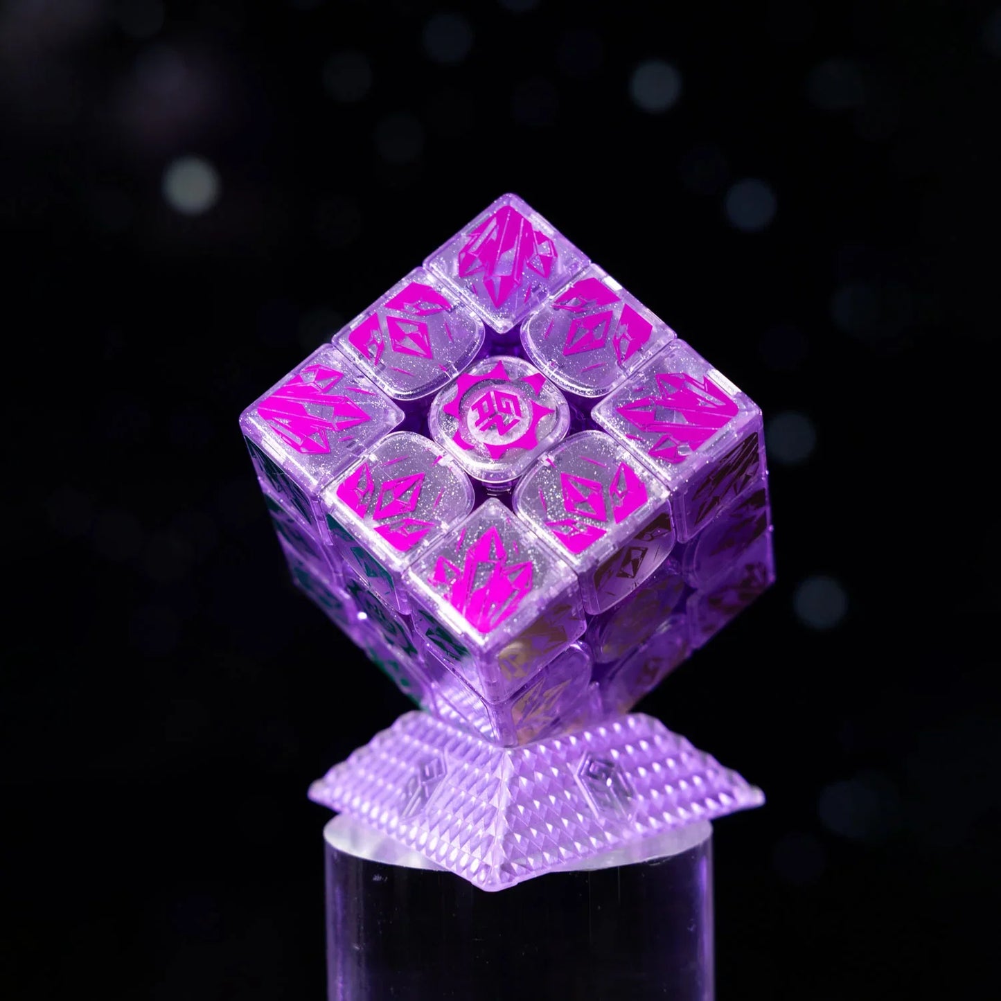 Transparent purple Gan16 Maglev MX Rubik's Cube with pink crystal-like symbols on textured stand