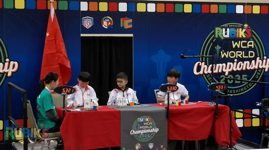 Young competitors solving speed cubes at the Rubik's WCA World Championship 2025 event table.