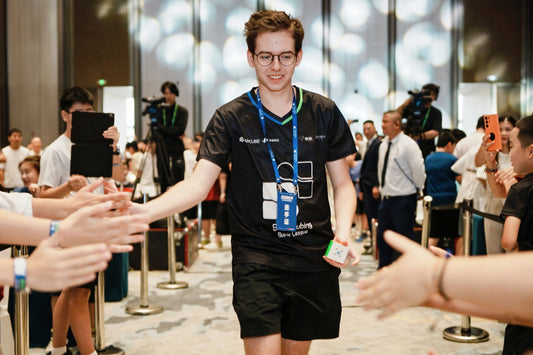 Young man in black speedcubing Super League shirt high-fiving fans at competition event