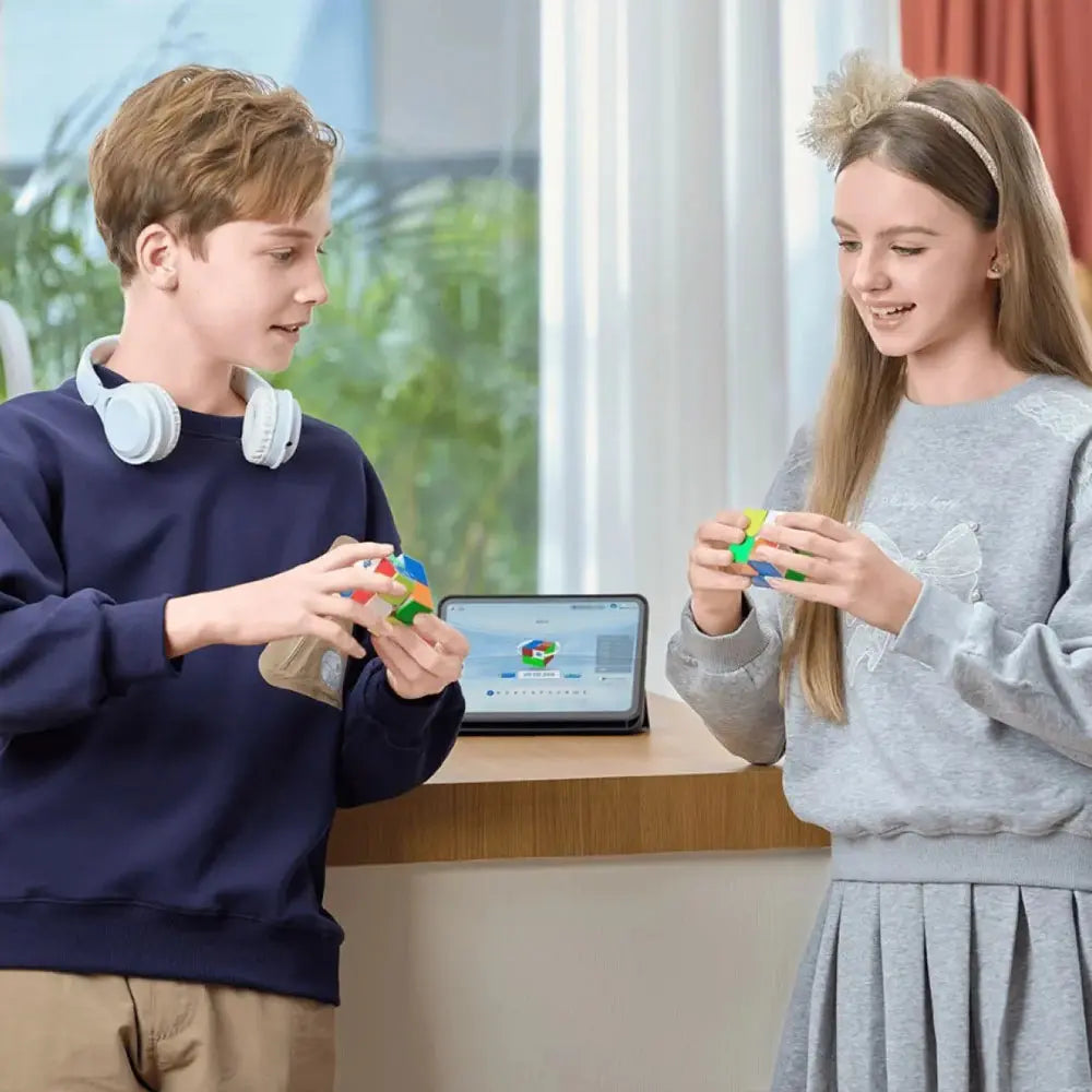 Two teenagers solving colorful GAN smart cubes indoors with a tablet showing cube app in the background