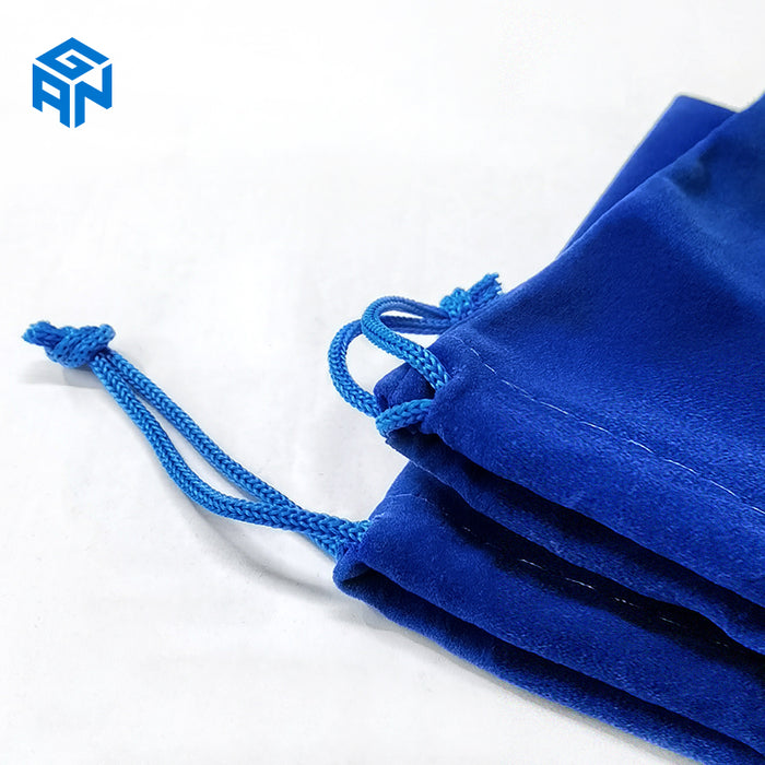 Close-up of blue velvet drawstring bag with braided cords on white background