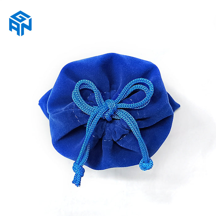Blue velvet drawstring pouch with blue braided cords tied in a bow on white background